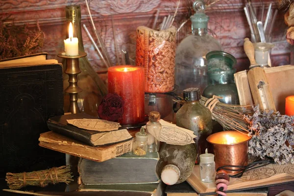 Kara büyü büyü. Wiccan büyüler ve otlar. Hala canlı: Eski yağ lambaları, antika kitap, bakır kase, ilaç şişeleri, lavanta, Pulsatilla pratensis bir antika arka plan üzerinde yanan bir muma gül tomurcukları kurutulmuş. Wicca arka plan.