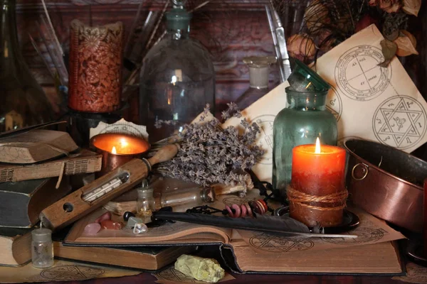 Kara büyü büyü. Wiccan büyüler ve otlar. Hala canlı: Eski yağ lambaları, antika kitap, bakır kase, ilaç şişeleri, lavanta, Pulsatilla pratensis bir antika arka plan üzerinde yanan bir muma gül tomurcukları kurutulmuş. Wicca arka plan.