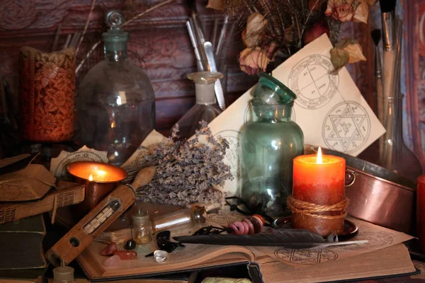 Kara büyü büyü. Wiccan büyüler ve otlar. Hala canlı: Eski yağ lambaları, antika kitap, bakır kase, ilaç şişeleri, lavanta, Pulsatilla pratensis bir antika arka plan üzerinde yanan bir muma gül tomurcukları kurutulmuş. Wicca arka plan.