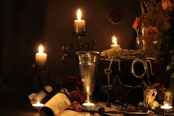 Kara büyü büyü. Wiccan büyüler ve otlar. Hala canlı: Eski yağ lambaları, antika kitap, bakır kase, ilaç şişeleri, lavanta, Pulsatilla pratensis bir antika arka plan üzerinde yanan bir muma gül tomurcukları kurutulmuş. Wicca arka plan.
