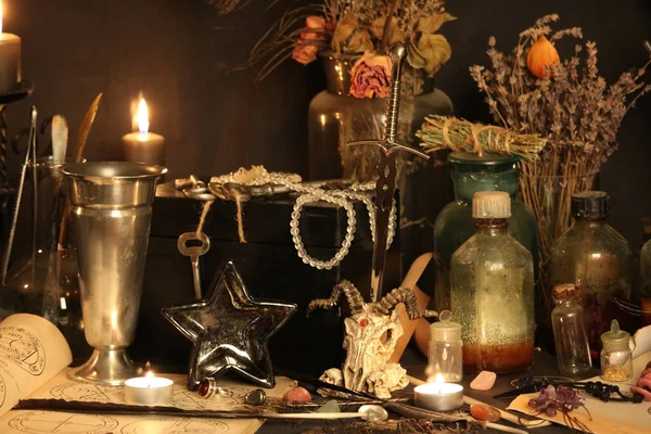 Kara büyü büyü. Wiccan büyüler ve otlar. Hala canlı: Eski yağ lambaları, antika kitap, bakır kase, ilaç şişeleri, lavanta, Pulsatilla pratensis bir antika arka plan üzerinde yanan bir muma gül tomurcukları kurutulmuş. Wicca arka plan.