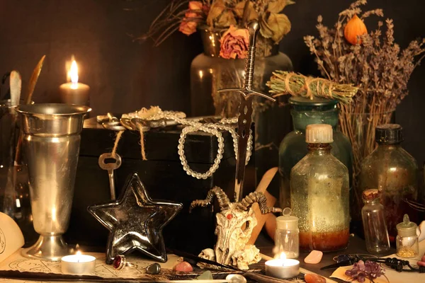 Black Magic Spells. Wiccan spells and herbs. Still Live: Old oil lamps, antique books, dried rose buds, a burning candle in a copper bowl, medicine bottles, lavender, Pulsatilla pratensis on an antique background. Wicca background.