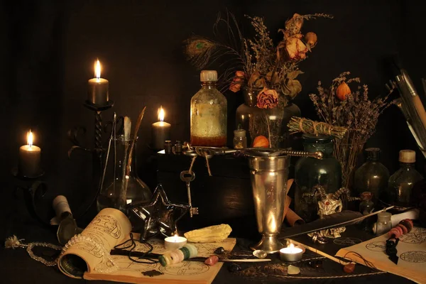 Kara büyü büyü. Wiccan büyüler ve otlar. Hala canlı: Eski yağ lambaları, antika kitap, bakır kase, ilaç şişeleri, lavanta, Pulsatilla pratensis bir antika arka plan üzerinde yanan bir muma gül tomurcukları kurutulmuş. Wicca arka plan.