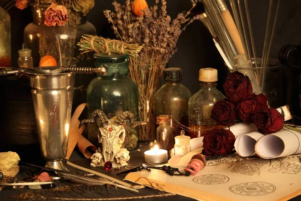 Black Magic Spells. Wiccan spells and herbs. Still Live: Old oil lamps, antique books, dried rose buds, a burning candle in a copper bowl, medicine bottles, lavender, Pulsatilla pratensis on an antique background. Wicca background.