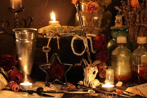 Black Magic Spells. Wiccan spells and herbs. Still Live: Old oil lamps, antique books, dried rose buds, a burning candle in a copper bowl, medicine bottles, lavender, Pulsatilla pratensis on an antique background. Wicca background.