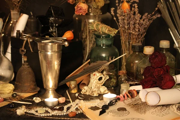 Kara büyü büyü. Wiccan büyüler ve otlar. Hala canlı: Eski yağ lambaları, antika kitap, bakır kase, ilaç şişeleri, lavanta, Pulsatilla pratensis bir antika arka plan üzerinde yanan bir muma gül tomurcukları kurutulmuş. Wicca arka plan.