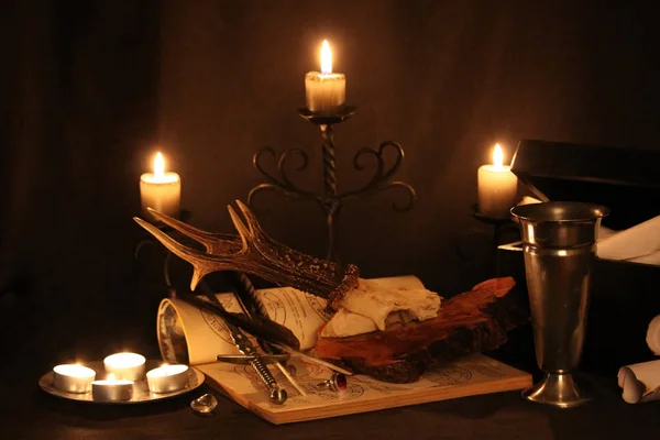 Black Magic Spells. Wiccan spells and herbs. Still Live: Old oil lamps, antique books, dried rose buds, a burning candle in a copper bowl, medicine bottles, lavender, Pulsatilla pratensis on an antique background. Wicca background.