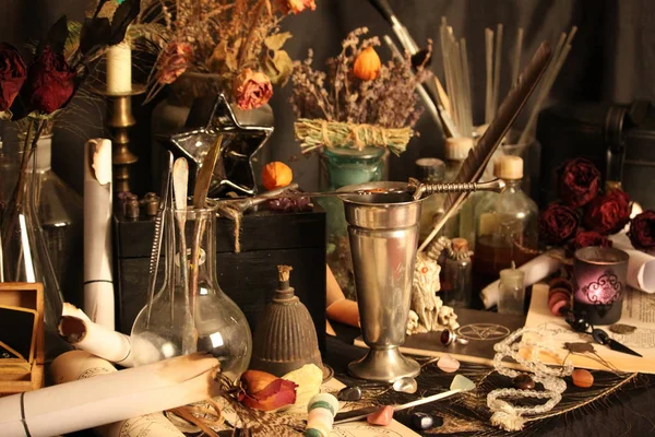 Black Magic Spells. Wiccan spells and herbs. Still Live: Old oil lamps, antique books, dried rose buds, a burning candle in a copper bowl, medicine bottles, lavender, Pulsatilla pratensis on an antique background. Wicca background.