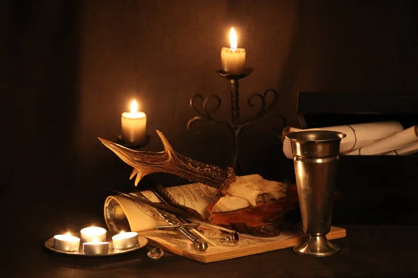 Black Magic Spells. Wiccan spells and herbs. Still Live: Old oil lamps, antique books, dried rose buds, a burning candle in a copper bowl, medicine bottles, lavender, Pulsatilla pratensis on an antique background. Wicca background.