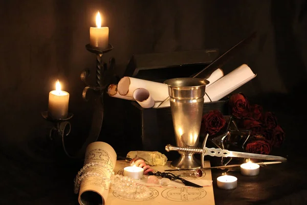 Black Magic Spells. Wiccan spells and herbs. Still Live: Old oil lamps, antique books, dried rose buds, a burning candle in a copper bowl, medicine bottles, lavender, Pulsatilla pratensis on an antique background. Wicca background.