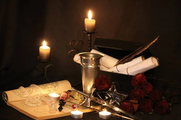 Black Magic Spells. Wiccan spells and herbs. Still Live: Old oil lamps, antique books, dried rose buds, a burning candle in a copper bowl, medicine bottles, lavender, Pulsatilla pratensis on an antique background. Wicca background.