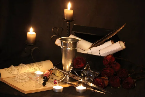 Black Magic Spells. Wiccan spells and herbs. Still Live: Old oil lamps, antique books, dried rose buds, a burning candle in a copper bowl, medicine bottles, lavender, Pulsatilla pratensis on an antique background. Wicca background.