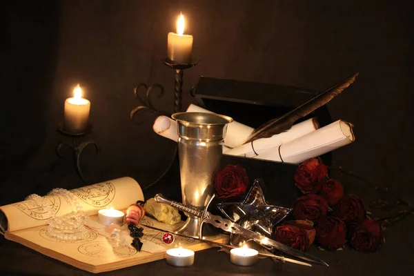 Black Magic Spells. Wiccan spells and herbs. Still Live: Old oil lamps, antique books, dried rose buds, a burning candle in a copper bowl, medicine bottles, lavender, Pulsatilla pratensis on an antique background. Wicca background.