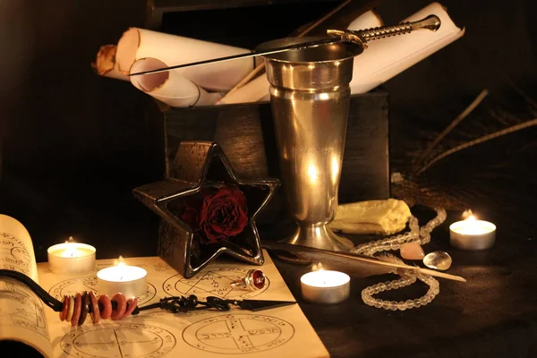 Black Magic Spells. Wiccan spells and herbs. Still Live: Old oil lamps, antique books, dried rose buds, a burning candle in a copper bowl, medicine bottles, lavender, Pulsatilla pratensis on an antique background. Wicca background.