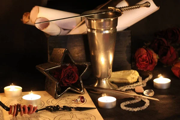 Black Magic Spells. Wiccan spells and herbs. Still Live: Old oil lamps, antique books, dried rose buds, a burning candle in a copper bowl, medicine bottles, lavender, Pulsatilla pratensis on an antique background. Wicca background.