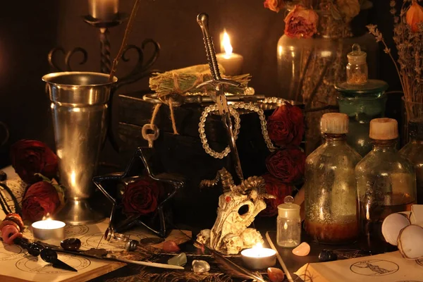 Kara büyü büyü. Wiccan büyüler ve otlar. Hala canlı: Eski yağ lambaları, antika kitap, bakır kase, ilaç şişeleri, lavanta, Pulsatilla pratensis bir antika arka plan üzerinde yanan bir muma gül tomurcukları kurutulmuş. Wicca arka plan.