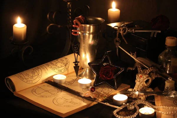 Black Magic Spells. Wiccan spells and herbs. Still Live: Old oil lamps, antique books, dried rose buds, a burning candle in a copper bowl, medicine bottles, lavender, Pulsatilla pratensis on an antique background. Wicca background.