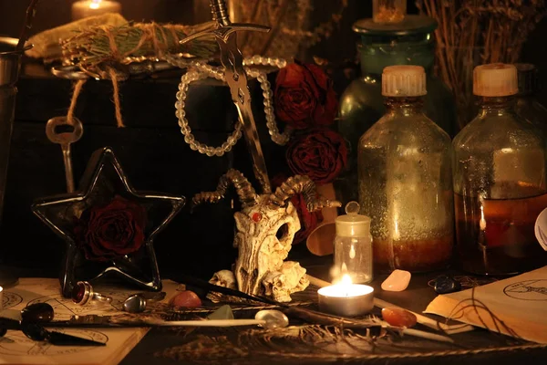 Black Magic Spells. Wiccan spells and herbs. Still Live: Old oil lamps, antique books, dried rose buds, a burning candle in a copper bowl, medicine bottles, lavender, Pulsatilla pratensis on an antique background. Wicca background.