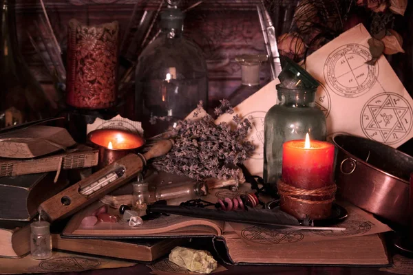 黑魔法咒语巫术法术和草药 仍然居住 老油灯 古色古香的书 干的玫瑰色芽 一根燃烧的蜡烛在铜碗 薰衣草 白头翁禾在古色古香的背景 巫术背景 图库照片