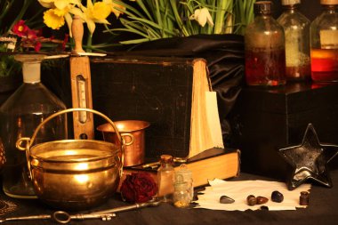 Kara büyü büyü. Wiccan büyüler ve otlar. Hala canlı: Eski yağ lambaları, antika kitap, bakır kase, ilaç şişeleri, lavanta, Pulsatilla pratensis bir antika arka plan üzerinde yanan bir muma gül tomurcukları kurutulmuş. Wicca arka plan.