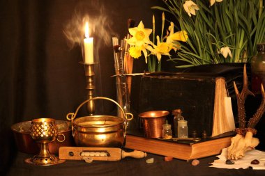 Kara büyü büyü. Wiccan büyüler ve otlar. Hala canlı: Eski yağ lambaları, antika kitap, bakır kase, ilaç şişeleri, lavanta, Pulsatilla pratensis bir antika arka plan üzerinde yanan bir muma gül tomurcukları kurutulmuş. Wicca arka plan.