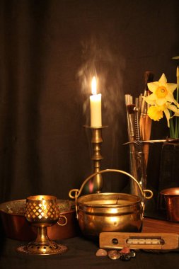 Kara büyü büyü. Wiccan büyüler ve otlar. Hala canlı: Eski yağ lambaları, antika kitap, bakır kase, ilaç şişeleri, lavanta, Pulsatilla pratensis bir antika arka plan üzerinde yanan bir muma gül tomurcukları kurutulmuş. Wicca arka plan.