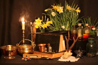 Kara büyü büyü. Wiccan büyüler ve otlar. Hala canlı: Eski yağ lambaları, antika kitap, bakır kase, ilaç şişeleri, lavanta, Pulsatilla pratensis bir antika arka plan üzerinde yanan bir muma gül tomurcukları kurutulmuş. Wicca arka plan.