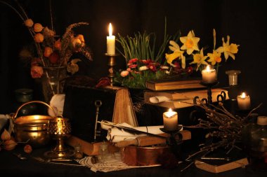 Kara büyü büyü. Wiccan büyüler ve otlar. Hala canlı: Eski yağ lambaları, antika kitap, bakır kase, ilaç şişeleri, lavanta, Pulsatilla pratensis bir antika arka plan üzerinde yanan bir muma gül tomurcukları kurutulmuş. Wicca arka plan.