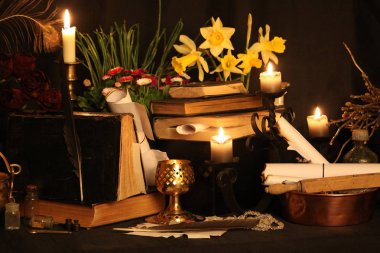 Kara büyü büyü. Wiccan büyüler ve otlar. Hala canlı: Eski yağ lambaları, antika kitap, bakır kase, ilaç şişeleri, lavanta, Pulsatilla pratensis bir antika arka plan üzerinde yanan bir muma gül tomurcukları kurutulmuş. Wicca arka plan.