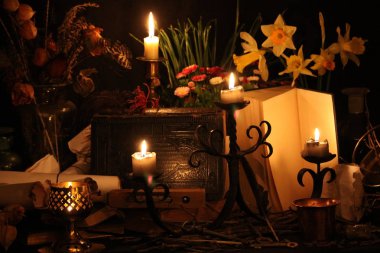 Kara büyü büyü. Wiccan büyüler ve otlar. Hala canlı: Eski yağ lambaları, antika kitap, bakır kase, ilaç şişeleri, lavanta, Pulsatilla pratensis bir antika arka plan üzerinde yanan bir muma gül tomurcukları kurutulmuş. Wicca arka plan.