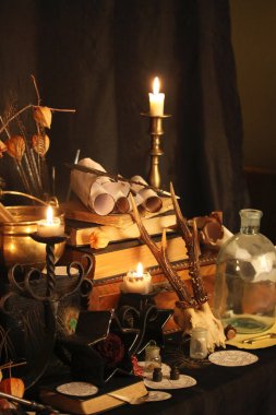 Kara büyü büyü. Wiccan büyüler ve otlar. Hala canlı: Eski yağ lambaları, antika kitap, bakır kase, ilaç şişeleri, lavanta, Pulsatilla pratensis bir antika arka plan üzerinde yanan bir muma gül tomurcukları kurutulmuş. Wicca arka plan.