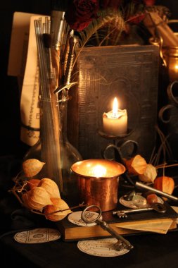 Kara büyü büyü. Wiccan büyüler ve otlar. Hala canlı: Eski yağ lambaları, antika kitap, bakır kase, ilaç şişeleri, lavanta, Pulsatilla pratensis bir antika arka plan üzerinde yanan bir muma gül tomurcukları kurutulmuş. Wicca arka plan.