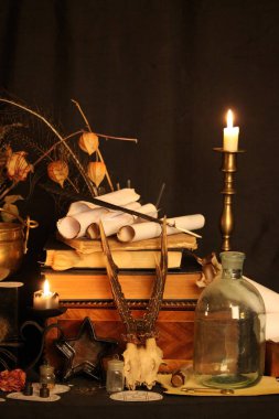 Kara büyü büyü. Wiccan büyüler ve otlar. Hala canlı: Eski yağ lambaları, antika kitap, bakır kase, ilaç şişeleri, lavanta, Pulsatilla pratensis bir antika arka plan üzerinde yanan bir muma gül tomurcukları kurutulmuş. Wicca arka plan.
