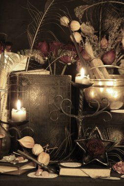 Kara büyü büyü. Wiccan büyüler ve otlar. Hala canlı: Eski yağ lambaları, antika kitap, bakır kase, ilaç şişeleri, lavanta, Pulsatilla pratensis bir antika arka plan üzerinde yanan bir muma gül tomurcukları kurutulmuş. Wicca arka plan.