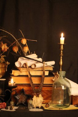Kara büyü büyü. Wiccan büyüler ve otlar. Hala canlı: Eski yağ lambaları, antika kitap, bakır kase, ilaç şişeleri, lavanta, Pulsatilla pratensis bir antika arka plan üzerinde yanan bir muma gül tomurcukları kurutulmuş. Wicca arka plan.