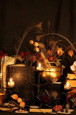 Kara büyü büyü. Wiccan büyüler ve otlar. Hala canlı: Eski yağ lambaları, antika kitap, bakır kase, ilaç şişeleri, lavanta, Pulsatilla pratensis bir antika arka plan üzerinde yanan bir muma gül tomurcukları kurutulmuş. Wicca arka plan.