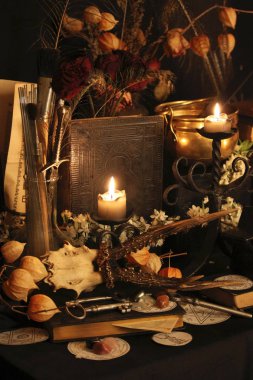 Kara büyü büyü. Wiccan büyüler ve otlar. Hala canlı: Eski yağ lambaları, antika kitap, bakır kase, ilaç şişeleri, lavanta, Pulsatilla pratensis bir antika arka plan üzerinde yanan bir muma gül tomurcukları kurutulmuş. Wicca arka plan.
