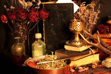 Kara büyü büyü. Wiccan büyüler ve otlar. Hala canlı: Eski yağ lambaları, antika kitap, bakır kase, ilaç şişeleri, lavanta, Pulsatilla pratensis bir antika arka plan üzerinde yanan bir muma gül tomurcukları kurutulmuş. Wicca arka plan.