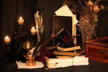 Kara büyü büyü. Wiccan büyüler ve otlar. Hala canlı: Eski yağ lambaları, antika kitap, bakır kase, ilaç şişeleri, lavanta, Pulsatilla pratensis bir antika arka plan üzerinde yanan bir muma gül tomurcukları kurutulmuş. Wicca arka plan.