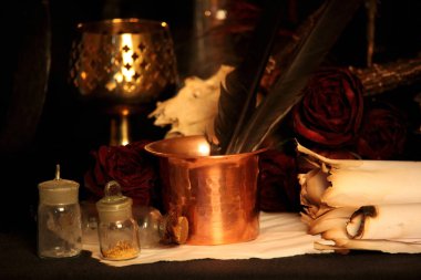 Kara büyü büyü. Wiccan büyüler ve otlar. Hala canlı: Eski yağ lambaları, antika kitap, bakır kase, ilaç şişeleri, lavanta, Pulsatilla pratensis bir antika arka plan üzerinde yanan bir muma gül tomurcukları kurutulmuş. Wicca arka plan.