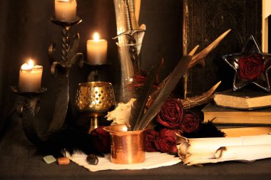 Kara büyü büyü. Wiccan büyüler ve otlar. Hala canlı: Eski yağ lambaları, antika kitap, bakır kase, ilaç şişeleri, lavanta, Pulsatilla pratensis bir antika arka plan üzerinde yanan bir muma gül tomurcukları kurutulmuş. Wicca arka plan.