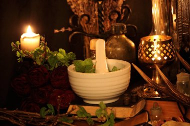 Kara büyü büyü. Wiccan büyüler ve otlar. Hala canlı: Eski yağ lambaları, antika kitap, bakır kase, ilaç şişeleri, lavanta, Pulsatilla pratensis bir antika arka plan üzerinde yanan bir muma gül tomurcukları kurutulmuş. Wicca arka plan.