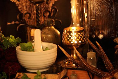 Kara büyü büyü. Wiccan büyüler ve otlar. Hala canlı: Eski yağ lambaları, antika kitap, bakır kase, ilaç şişeleri, lavanta, Pulsatilla pratensis bir antika arka plan üzerinde yanan bir muma gül tomurcukları kurutulmuş. Wicca arka plan.