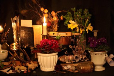 Kara büyü büyü. Wiccan büyüler ve otlar. Hala canlı: Eski yağ lambaları, antika kitap, bakır kase, ilaç şişeleri, lavanta, Pulsatilla pratensis bir antika arka plan üzerinde yanan bir muma gül tomurcukları kurutulmuş. Wicca arka plan.