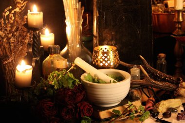 Kara büyü büyü. Wiccan büyüler ve otlar. Hala canlı: Eski yağ lambaları, antika kitap, bakır kase, ilaç şişeleri, lavanta, Pulsatilla pratensis bir antika arka plan üzerinde yanan bir muma gül tomurcukları kurutulmuş. Wicca arka plan.