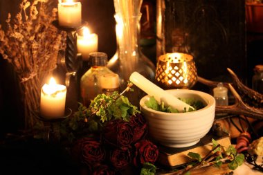 Kara büyü büyü. Wiccan büyüler ve otlar. Hala canlı: Eski yağ lambaları, antika kitap, bakır kase, ilaç şişeleri, lavanta, Pulsatilla pratensis bir antika arka plan üzerinde yanan bir muma gül tomurcukları kurutulmuş. Wicca arka plan.