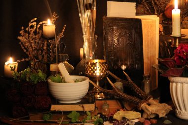 Kara büyü büyü. Wiccan büyüler ve otlar. Hala canlı: Eski yağ lambaları, antika kitap, bakır kase, ilaç şişeleri, lavanta, Pulsatilla pratensis bir antika arka plan üzerinde yanan bir muma gül tomurcukları kurutulmuş. Wicca arka plan.