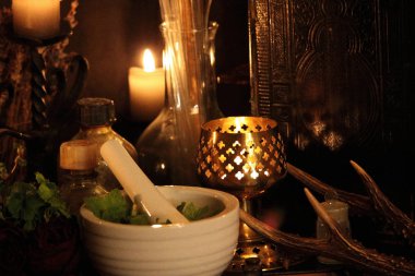Kara büyü büyü. Wiccan büyüler ve otlar. Hala canlı: Eski yağ lambaları, antika kitap, bakır kase, ilaç şişeleri, lavanta, Pulsatilla pratensis bir antika arka plan üzerinde yanan bir muma gül tomurcukları kurutulmuş. Wicca arka plan.