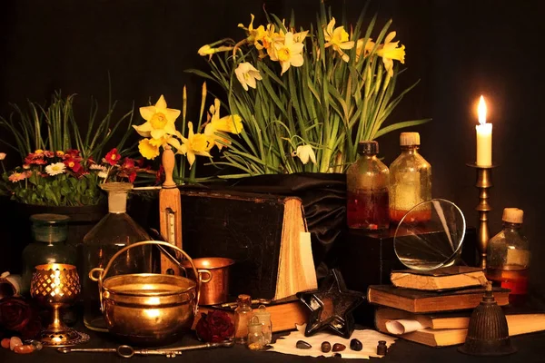 Kara büyü büyü. Wiccan büyüler ve otlar. Hala canlı: Eski yağ lambaları, antika kitap, bakır kase, ilaç şişeleri, lavanta, Pulsatilla pratensis bir antika arka plan üzerinde yanan bir muma gül tomurcukları kurutulmuş. Wicca arka plan.