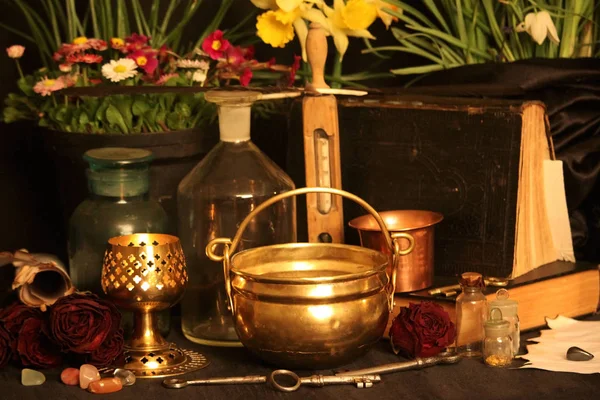 Black Magic Spells. Wiccan spells and herbs. Still Live: Old oil lamps, antique books, dried rose buds, a burning candle in a copper bowl, medicine bottles, lavender, Pulsatilla pratensis on an antique background. Wicca background.